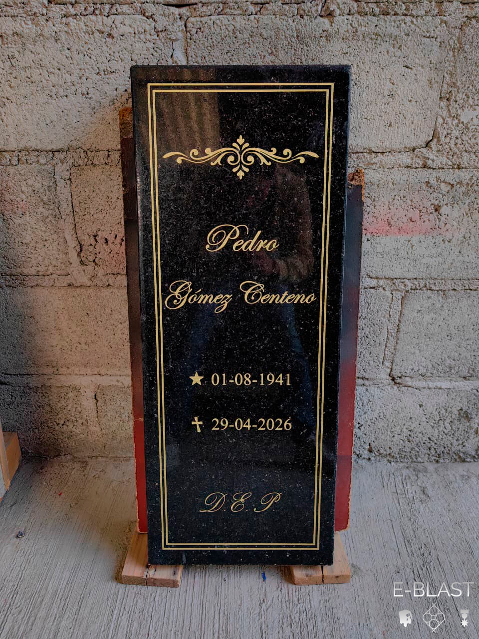 Placa oscura con texto y ornamentos en color dorado